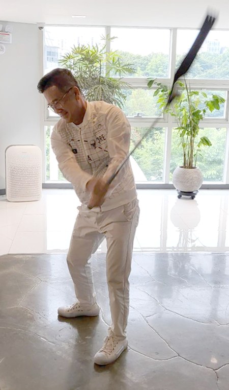 Chilho Lee, CEO of Woosung Distribution, swinging the SmartGolf AIX in his office